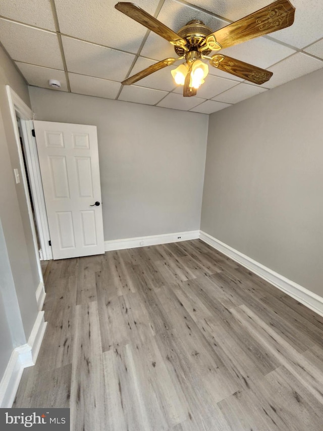 empty room with hardwood / wood-style flooring, a drop ceiling, and ceiling fan