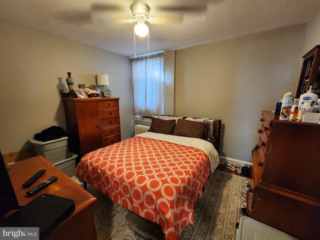 bedroom with ceiling fan, dark hardwood / wood-style floors, and radiator