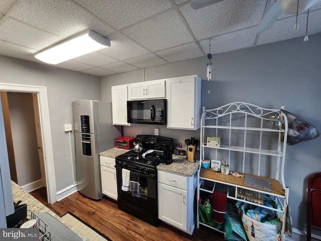 kitchen featuring white cabinets, dark hardwood / wood-style flooring, a drop ceiling, and black appliances