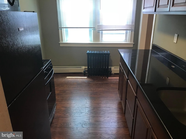 kitchen featuring a baseboard heating unit, black fridge, dark wood-type flooring, and radiator