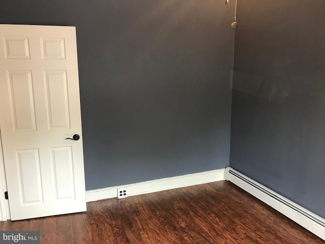 unfurnished room with hardwood / wood-style flooring and a baseboard heating unit