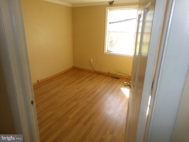 spare room featuring ornamental molding and light wood-type flooring