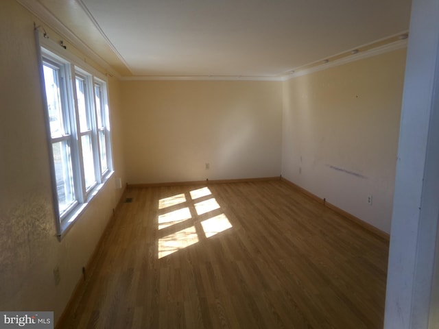 empty room with crown molding and wood-type flooring