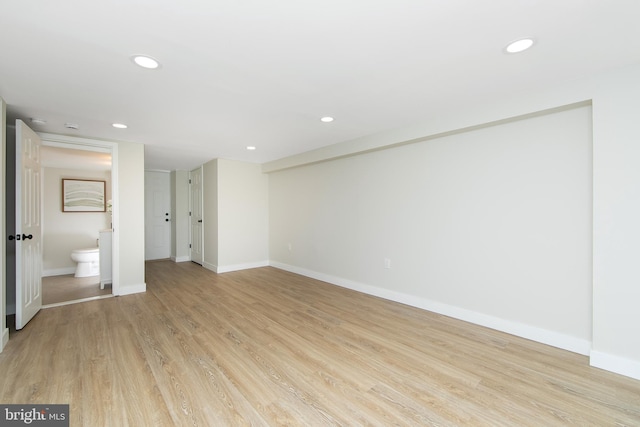 spare room featuring ensuite bathroom and light wood-type flooring