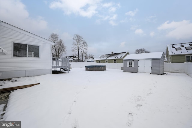 yard layered in snow featuring a swimming pool side deck and a shed