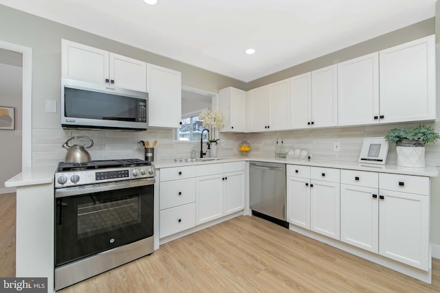 kitchen featuring white cabinetry, sink, decorative backsplash, light hardwood / wood-style floors, and stainless steel appliances