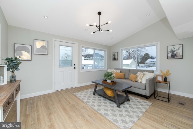 living room featuring light hardwood / wood-style flooring, a notable chandelier, plenty of natural light, and vaulted ceiling