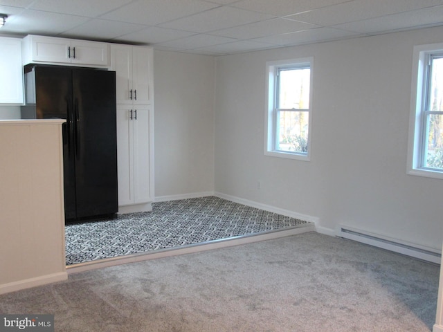 spare room featuring a baseboard radiator, baseboards, light colored carpet, and a drop ceiling