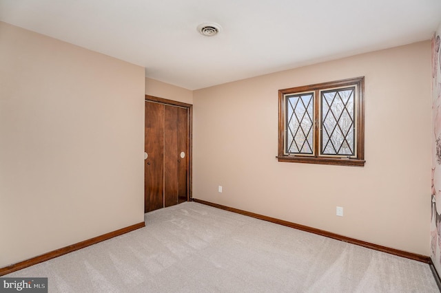 unfurnished bedroom featuring light carpet and a closet