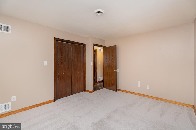 unfurnished bedroom featuring light colored carpet and a closet