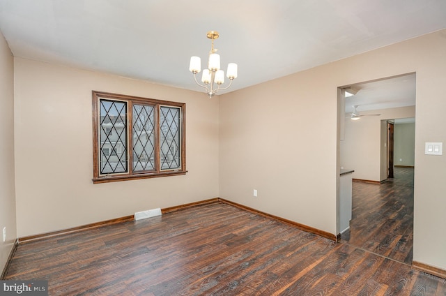 empty room featuring dark hardwood / wood-style flooring and a notable chandelier