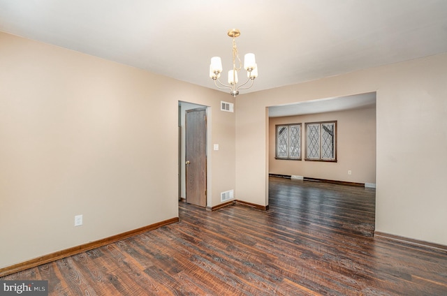 empty room featuring an inviting chandelier and dark wood-type flooring