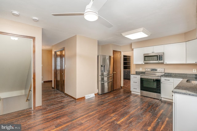 kitchen with dark wood-type flooring, ceiling fan, appliances with stainless steel finishes, and white cabinets