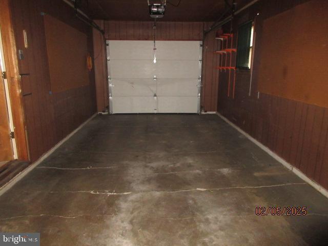 garage with a garage door opener and wooden walls