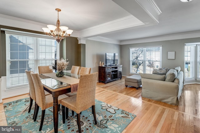 dining space with light wood-style floors, crown molding, baseboards, and a notable chandelier