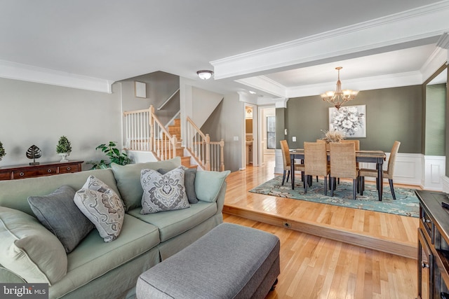 living room with stairs, ornamental molding, wood finished floors, and wainscoting