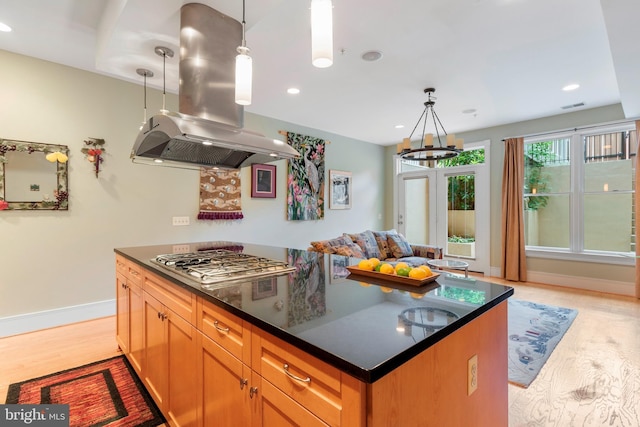 kitchen featuring island range hood, a kitchen island, stainless steel gas stovetop, and hanging light fixtures