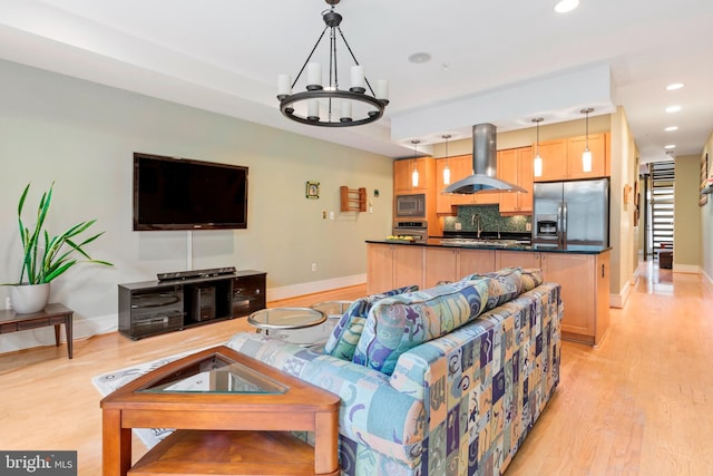 living room featuring an inviting chandelier, sink, and light hardwood / wood-style flooring