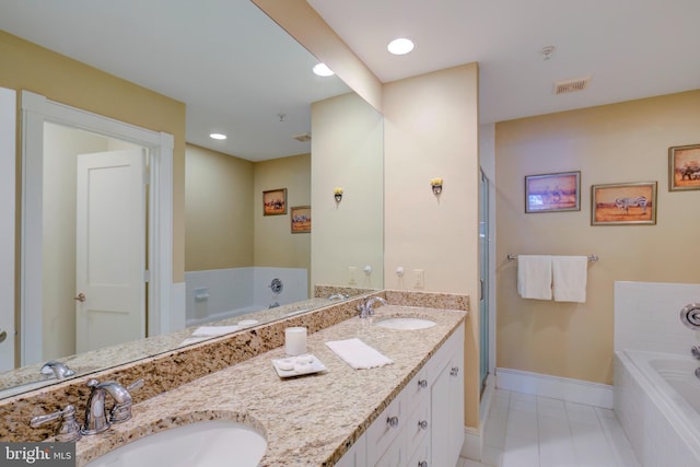 bathroom with vanity, tiled bath, and tile patterned flooring