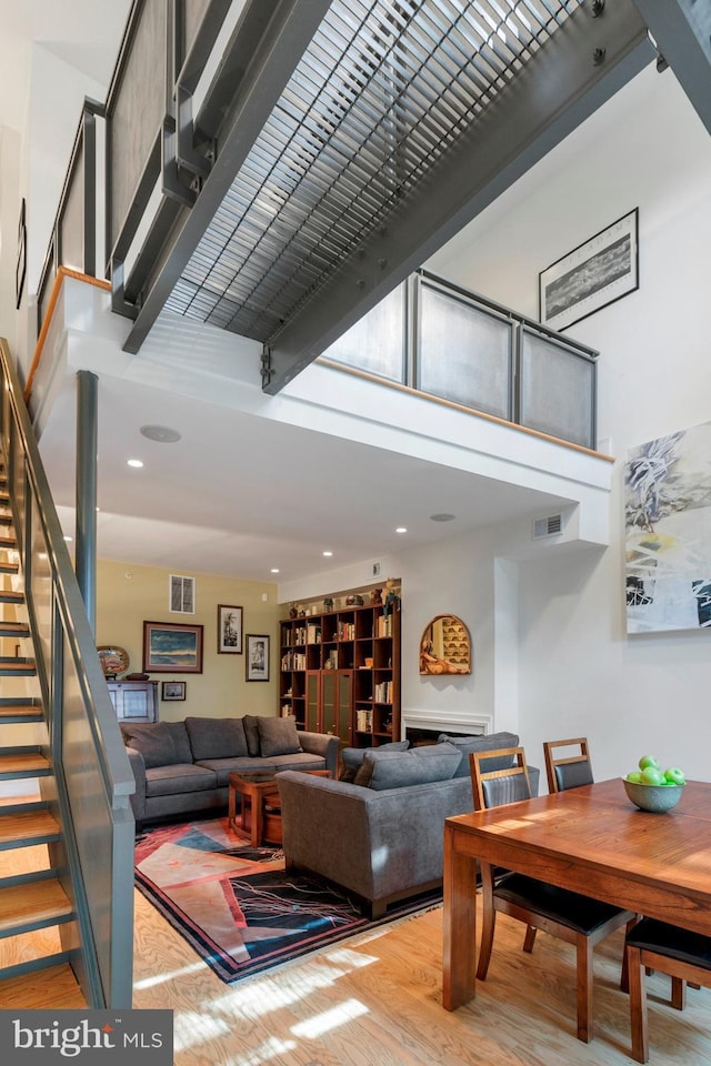 living room with a towering ceiling and light wood-type flooring