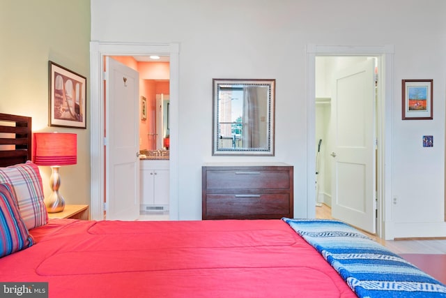 bedroom featuring ensuite bathroom and hardwood / wood-style floors