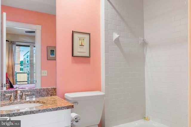 full bathroom with tiled shower / bath, vanity, and toilet