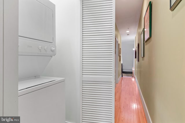 laundry room with stacked washer and clothes dryer and hardwood / wood-style floors