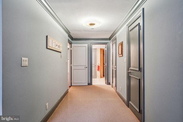 hallway featuring ornamental molding, light carpet, and baseboards