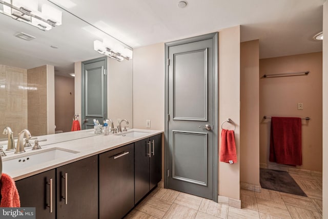 bathroom with double vanity, baseboards, and a sink