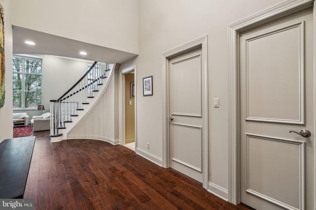 foyer with stairs, baseboards, dark wood-type flooring, and recessed lighting