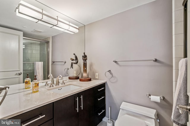 full bathroom with visible vents, vanity, a tile shower, and toilet