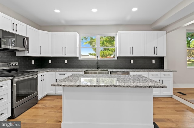 kitchen with sink, stainless steel appliances, white cabinets, and a kitchen island