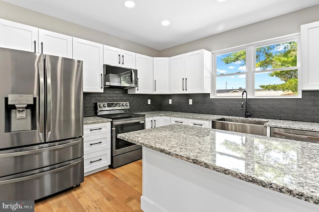 kitchen featuring sink, light hardwood / wood-style flooring, appliances with stainless steel finishes, white cabinetry, and light stone counters