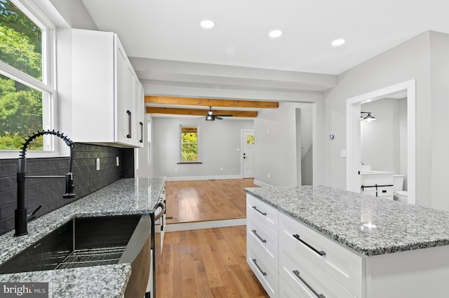 kitchen featuring white cabinetry, sink, and light stone countertops