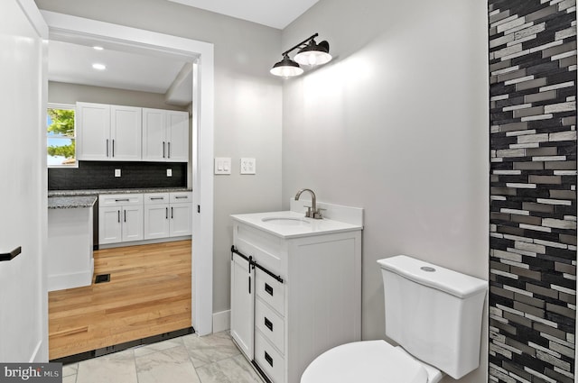 bathroom with tasteful backsplash, vanity, and toilet