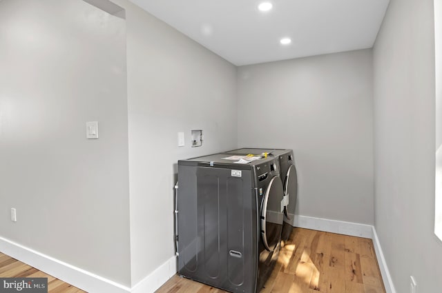 clothes washing area with hardwood / wood-style flooring and separate washer and dryer