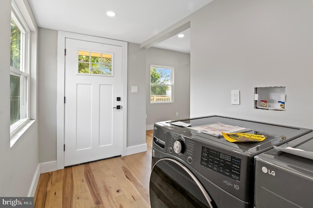 laundry area with washer and clothes dryer and light hardwood / wood-style flooring