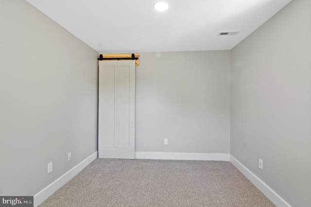 unfurnished room with a barn door and carpet