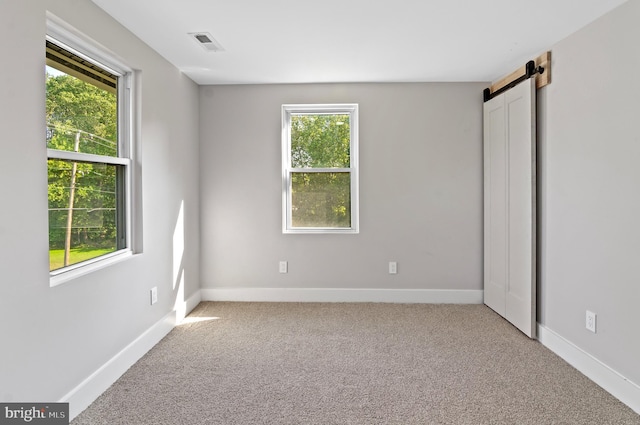 unfurnished bedroom featuring light carpet and a barn door