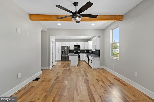 kitchen with tasteful backsplash, beamed ceiling, stainless steel appliances, and white cabinets