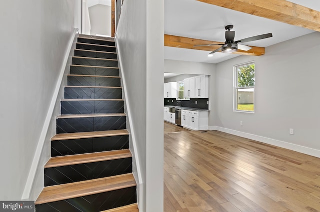 stairs featuring ceiling fan, hardwood / wood-style floors, and beam ceiling