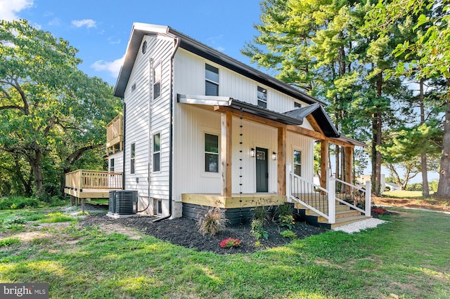 view of front facade featuring a porch, central air condition unit, and a front lawn