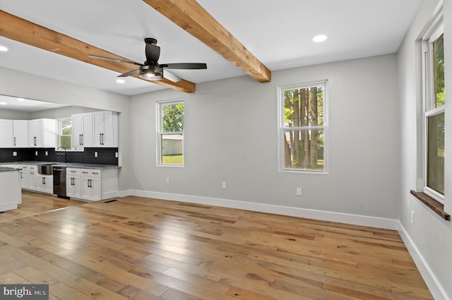 kitchen featuring white cabinetry, decorative backsplash, beam ceiling, and light wood-type flooring