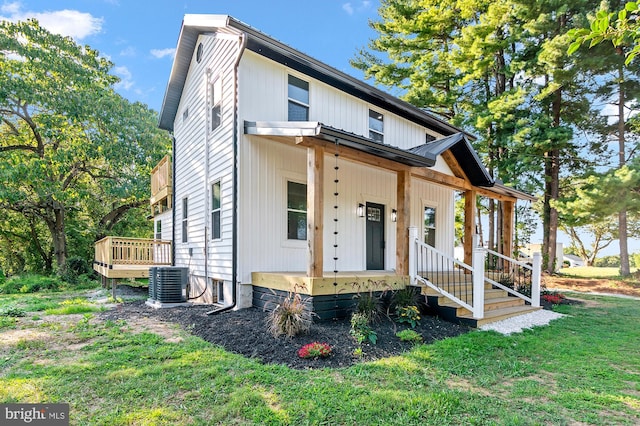 view of front of property featuring cooling unit, covered porch, and a front lawn