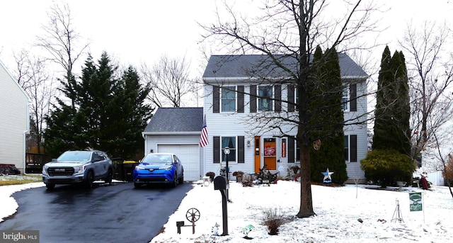 colonial house with aphalt driveway, an attached garage, and roof with shingles