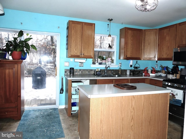 kitchen with sink, a kitchen island, pendant lighting, a healthy amount of sunlight, and black gas range