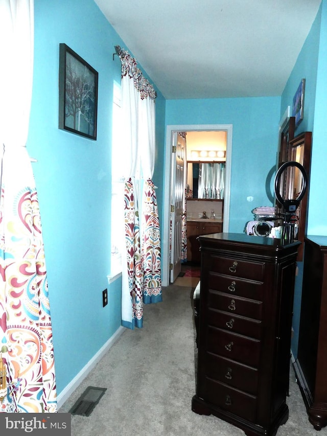 bedroom with connected bathroom and light colored carpet