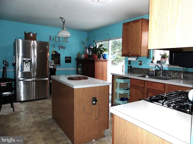 kitchen with a center island, sink, stainless steel fridge, and decorative light fixtures