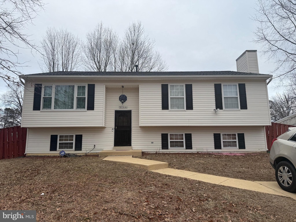 bi-level home with fence and a chimney