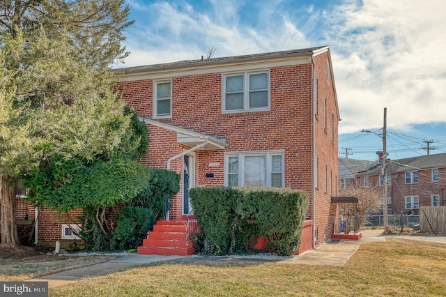 view of front of home with brick siding, fence, and a front lawn